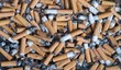 Gerauchte Zi­ga­ret­ten­stum­mel liegen in Asche - Hintergrund