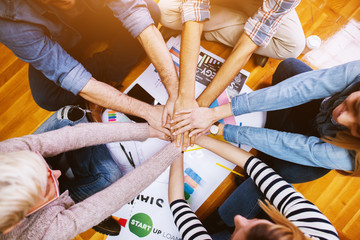 Group of excited and confident young people sitting in a row in the waiting room with a folder in hand before an interview with the entrepreneur and sharing personal details.