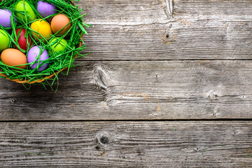 Wall Mural - Wooden background with easter eggs in the basket, top view