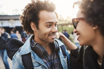 Wall Mural - Close-up portrait of african-american couple in trendy clothes and afro haircuts, hugging while smiling and looking at each other, standing in park. Couple in love spending weekends outdoors