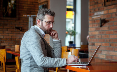 Wall Mural - Middle age man using laptop in the cafe