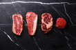 Variety of Raw Black Angus Prime meat steaks Blade on bone, Striploin, Rib eye, Tenderloin fillet mignon on dark marble background copy space