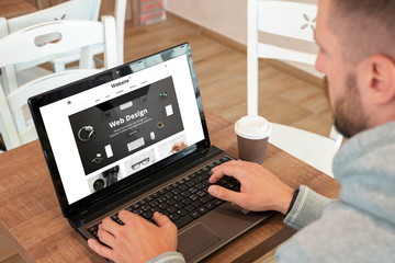 Leinwandbilder - Web design company responsive web site on laptop display. Guy watch site and drink coffee.