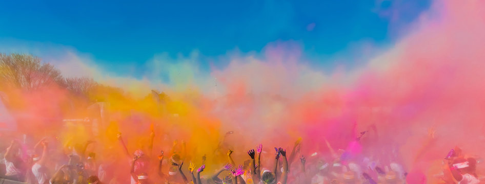 crowd throwing bright coloured powder paint in the air, holi festival dahan