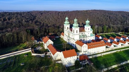 Wall Mural - Camaldolese monastery and baroque church in the wood on the hill in Bielany, Krakow, Poland , Aerial 4K video in sunset light in winter with Vistula River and far view of Cracow city in the background