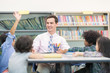 © Nattanon - Happy Children and teacher in Learning Class at Library. Boy raised hand up his hand to answer a question from teacher. Setup studio shooting.