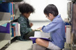 © Nattanon - Little Asian spectacles Boy and his happy African boy. Happy Children Learning Class in Library. Development of Human Resources in Education Concept. Setup studio shooting.