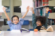 © Nattanon - Little Asian spectacles Boy and his happy African boy. Raising Hands up in Library.Education Concept. Setup studio shooting.