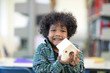 © Nattanon - Very happy African ethnicity boy with little White House Wooden in hands laughing happy. Children Learning Class in Library. Setup studio shooting.