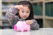 © Nattanon - Selective focus at pig jar. Kids playing collect money with a pink saving Pig Jar in the Library. Setup studio shooting.