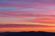 © Massimo - Clouds and jet vapor trails creating beautiful, colorful texture in the sky at sunset with mountain profiles on the low part of the frame