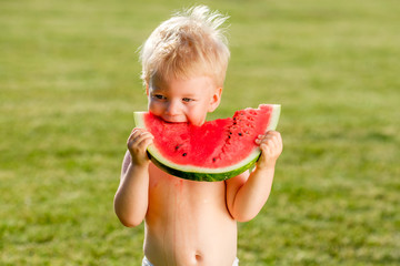 Wall Mural - One year old baby boy eating watermelon in the garden