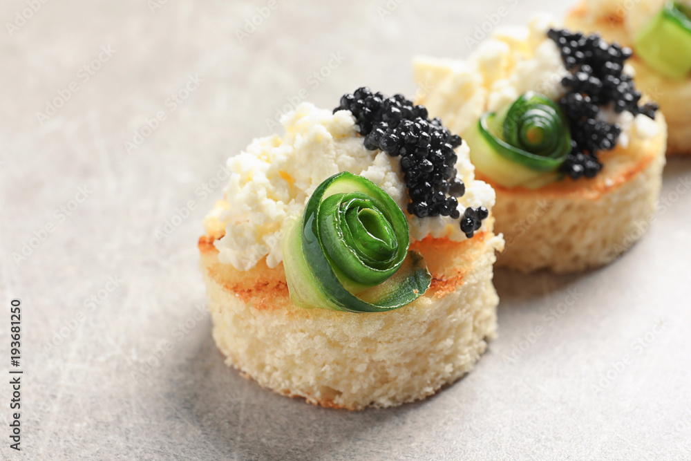 Tasty black caviar appetizer on grey background