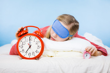 Sleeping woman wearing pajamas holding clock