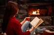 © luckybusiness - girl reading book in front of fireplace and relaxing