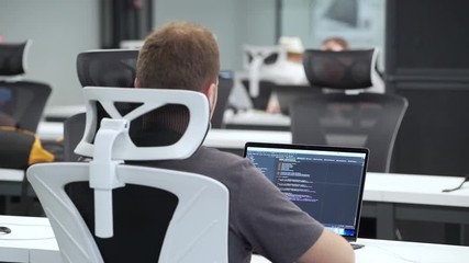 Programmer works on laptop in the office.