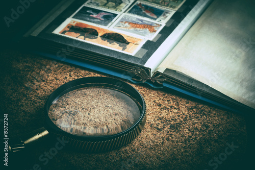 Plakat Book with postage stamps and a magnifying glass.