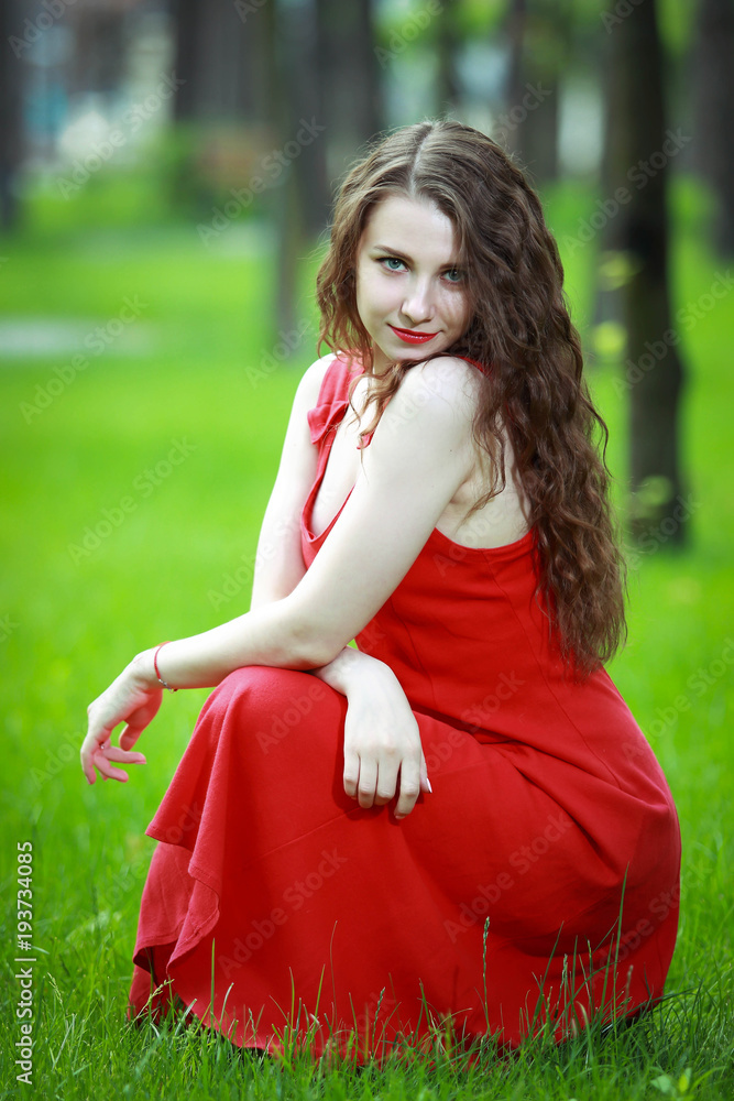 Красивая девушка в красном платье в парке.