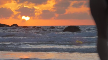 Wall Mural - sunset sea, tropical beach, two girls running out into the water with joy making splashes in slowmot