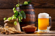 Mug of beer with green hops, wheat ears and wooden barrel