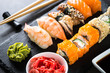 Sushi and sushi roll set on black stone table.