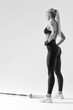 © USM Photography - Black and white image of fit young female athlete prepare lifting heavy weights Rear view of power attractive young woman with barbell Bodybuilder female model performing barbell squat