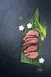 Japanese barbecue wagyu aged fillet steak slices with daikon and leek as top view on a banana leaf