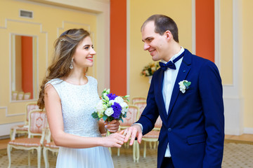 Bridal bouquet and wedding rings on the hands of the bride and groom