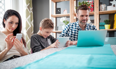 Family with laptop, tablet and smartphone, everyone using digital devices