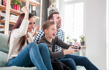 Excited family playing video game on the console at home