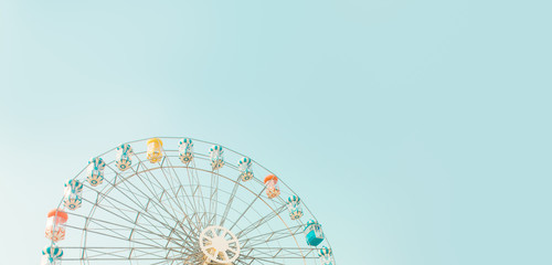 Retro colorful ferris wheel of the amusement park in the blue sky background.