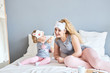 © Yuliya - Mother and daughter posing happily in bed.  a little girl is feeding her mother ice cream.