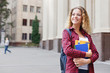 © Prostock-studio - Beautiful female student standing in front of the university campus