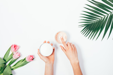 Palm leaf, bouquet of pink tulips and cosmetic cream