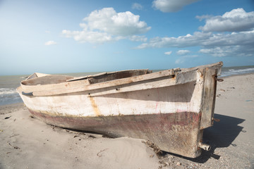 Wall Mural - fisherman boat abandoned in the sand on the shore of the beach