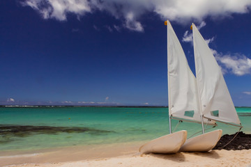 two dinghy sailing boats on a sandy beach