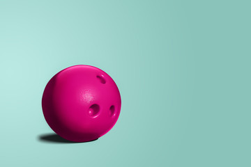 Pink bowling ball. A toy bowling ball of pink color on a blue, turquoise pastel background. A minimalist concept, abstract. The concept of having fun, going out with friends.