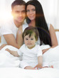 © ASDF - Portrait of a joyful family sitting on the bed at home