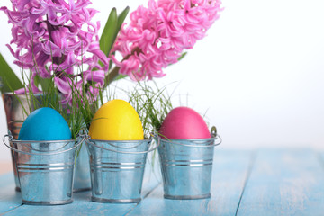 Wall Mural - Easter eggs on a blue wooden table.Three colorfull egg in metal bucket.Flower hyacinth in bucket.Copy space.Eater background.Pastel colour