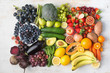 Healthy eating concept, assortment of rainbow fruits and vegetables, berries, bananas, oranges, grapes, broccoli, beetroot on the off white table arranged in a rectangle, top view, selective focus