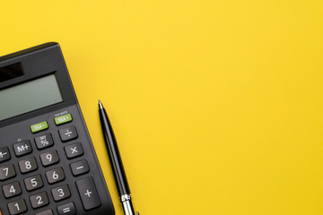 Flat lay or top view of black pen with calculator on vivid yellow background table with blank copy space, math, cost, tax or investment calculation