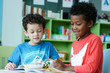 © mangpor2004 - American and African boys are reading together with happiness in their kindergarten classroom, kid education and diversity concept
