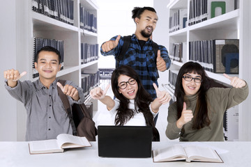 Canvas Print - Multiracial students showing thumbs up in the library