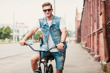 Wall Mural - Handsome hipster enjoying city ride by bicycle.