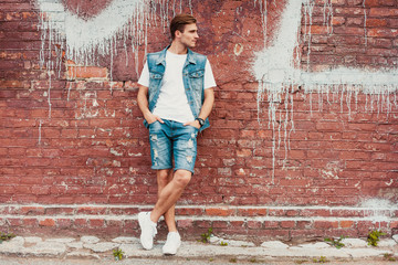 Wall Mural - Young man standing against a brick wall