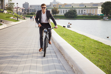 Wall Mural - Businessman riding bicycle to work on urban street in morning.