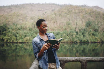 Wall Mural - African American woman alone in nature reading a book leisure concept