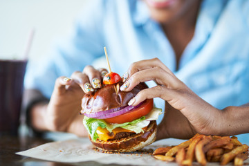 Wall Mural - close up of african american woman about to eat vegan meatless cheese burger at restaurant