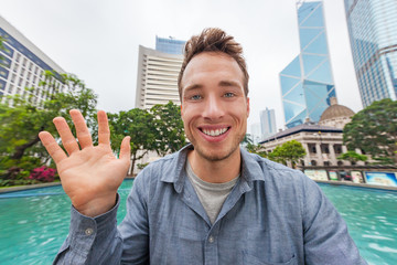 Selfie man waving hello talking to camera chatting online on video conference or recording videoblog vlog vlogging for social media app. Young people trave lifestyle in Hong Kong, China, Asia.