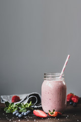 Wall Mural - Pink strawbery smoothie in jar with drinking straw on grey background with copy space for text